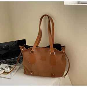 Detail showing brown suede texture, leather straps and metal rivets on the large tote bag