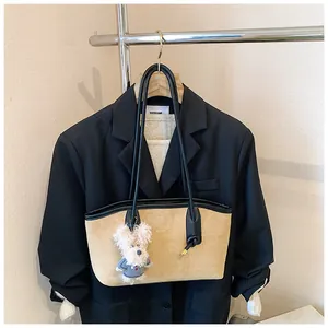 Détail du sac bandoulière en daim avec un charmant chiot en peluche sur la lanière en cuir