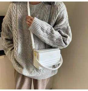 Detalle del bolso caja blanco con textura plisada, hebilla dorada y correa ajustable