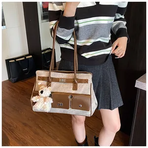 Detail of retro tote bag with texture fabric, brown leather trim, and plush bear charm