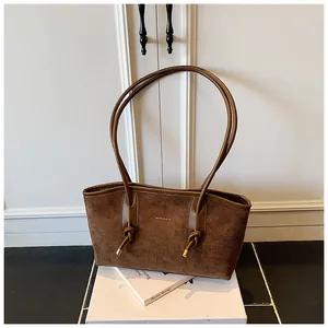 Détail du sac cabas en daim marron foncé avec fines bretelles nouées et garnitures dorées