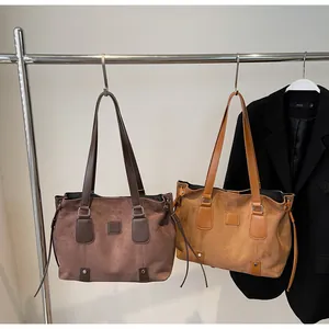 Detail of large suede tote bags in coffee and camel colors on minimalist hangers