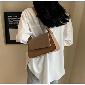 Detail view of caramel brown handbag with woven texture flap on a female model