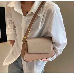 Detail of a vintage-style crossbody bag with woven fabric flap and gold metal buckle