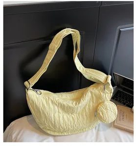 Detailed view of light yellow pleated hobo bag with matching round coin purse charm