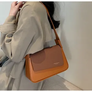 Détail du sac à bandoulière en cuir caramel avec rabat texturé café et logo doré