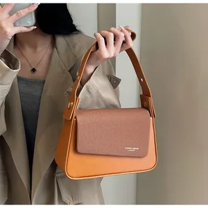 Detail of the brown orange shoulder bag showing mixed leather texture and gold rivets