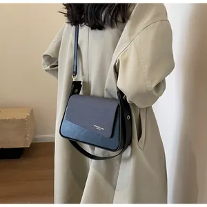 Detail of a black and grey leather crossbody bag showing the fashion logo and strap