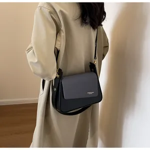 Detail of cross-body bag with grey twill fabric flap and black leather finish