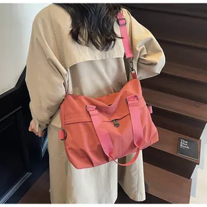 Detail view of large coral nylon crossbody bag showing wide strap and durable texture