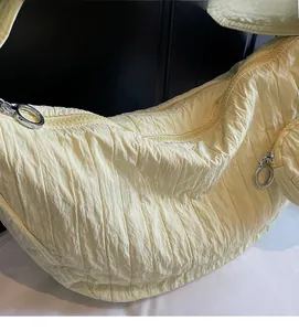 Detail of light yellow pleated nylon shoulder bag with silver circular metal zipper