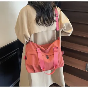 Detail of coral nylon shoulder bag with adjustable strap on a female model