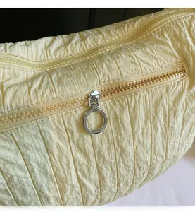 Detail of smooth metal zipper and pleated quilted fabric on yellow tote bag