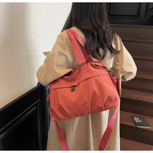 Detailed view of the large orange nylon crossbody bag with casual pleated design and strap