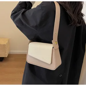 Détail du sac bandoulière bicolore montrant la boucle et la texture du cuir sur le mannequin