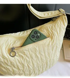 Detail of light yellow pleated tote bag showing a functional front zipper pocket for mobile