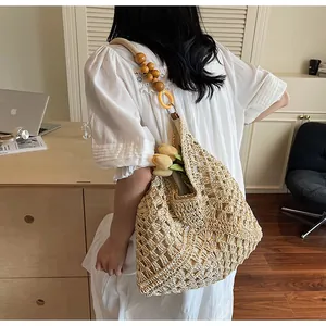 Detail of woven tote bag with wooden bead straps and tulip decor on model's shoulder