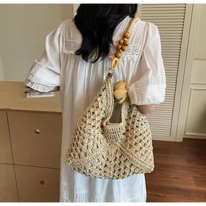Close-up of woven straw tote bag with unique round wooden bead shoulder straps