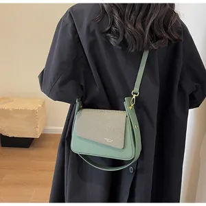 Détail du sac hobo vert sauge avec rabat texturé et lettrage doré à l'épaule
