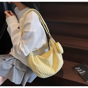 Detail view of a pale yellow pleated hobo bag with a matching round coin purse pendant