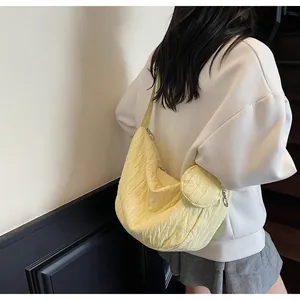 Detail of light yellow pleated shoulder bag with vertical texture and small round coin purse