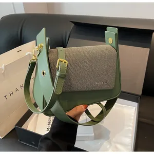 Detail of green leather and beige twill fabric handbag with gold hardware accents