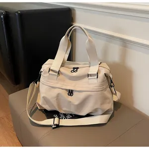Detail view of large cream nylon travel bag with black zippers and adjustable strap