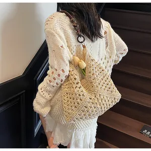 Detailed close-up of a hand-woven beige straw tote bag featuring decorative wooden beads
