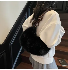 Detail of black faux fur crescent bag with wooden bead shoulder strap on a model