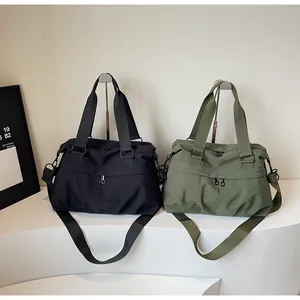Detail view of large nylon travel bags in black and olive green with adjustable straps