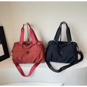 Detail view of large nylon travel bags in black and red with adjustable shoulder straps