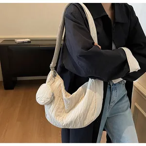 Detail of a pleated crescent crossbody bag in cream white with mini coin purse accessory