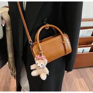 Detail of vintage leather tote with bear charm on adjustable shoulder strap