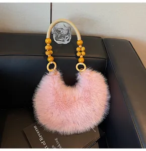Pink plush crescent bag featuring distinctive yellow bead strap and woven handle detail