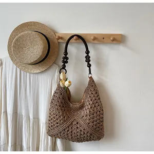Detail of hand-woven straw hobo bag featuring dark brown wooden beaded handle and lining