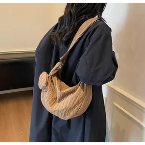 Detail of a brown pleated crescent bag with a wide strap and small round pouch attachment