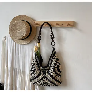 Detail of woven straw tote bag featuring contrast geometric patterns and wooden bead handles