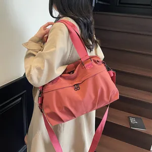 Large coral pink nylon travel bag with dual handles and crossbody strap on staircase