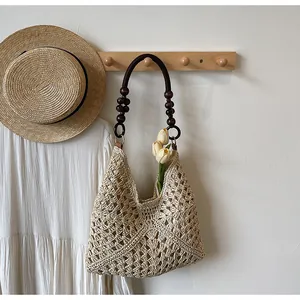 Detail of hand-woven straw tote with wooden bead straps and elegant hollow crochet pattern