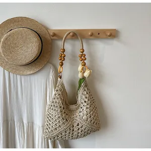 Detail of hand-woven crochet tote bag with decorative wooden bead shoulder straps