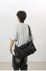 Model wearing a large black commuter crossbody bag with adjustable buckle straps