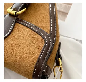 Detalle de costuras en contraste y herrajes dorados en bolso de cuero esmerilado