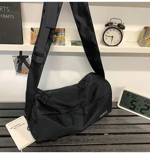 Detailed close-up of large black nylon messenger bag with multiple zippers and wide strap