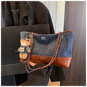 Detail of blue denim and brown leather patchwork tote bag with silver metal swivel lock