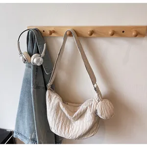 Detail of beige quilted crescent tote with matching small round coin purse attachment