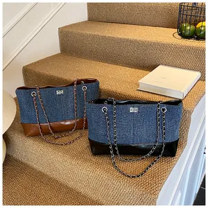 Detail of denim tote bags with leather trim, metal turn-locks, and chain shoulder straps