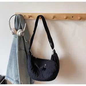 Detail of black pleated shoulder bag with small round coin purse on a wall hook