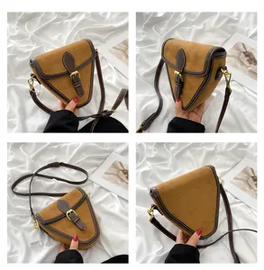 Detalle de bolso bandolera triangular de ante marrón con hebilla y costuras blancas
