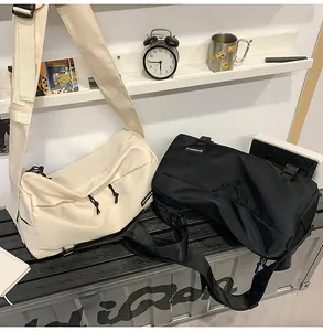 Detail of adjustable straps and buckle closures on black and cream messenger bags