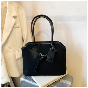 Detail van zwarte suède shopper met laklederen handvatten op een zilveren koffer